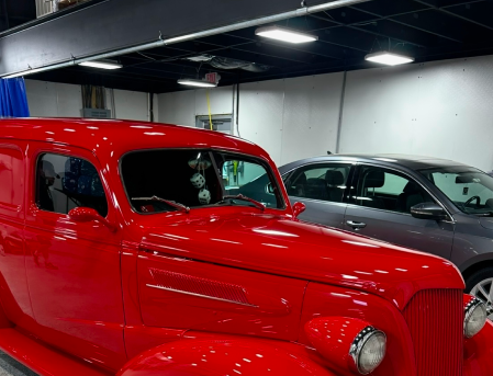 Shiny red vintage car in an indoor showroom beside a silver modern car