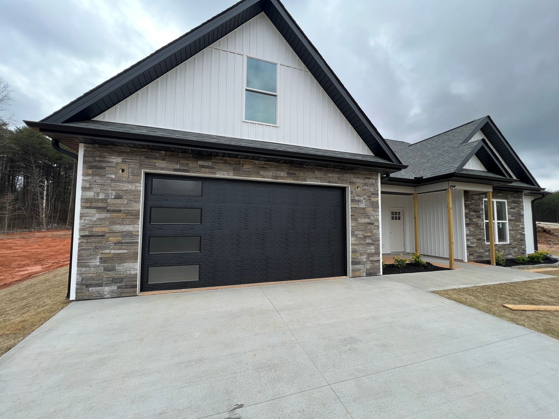 New house exterior with black garage door, stone facade, and white siding.