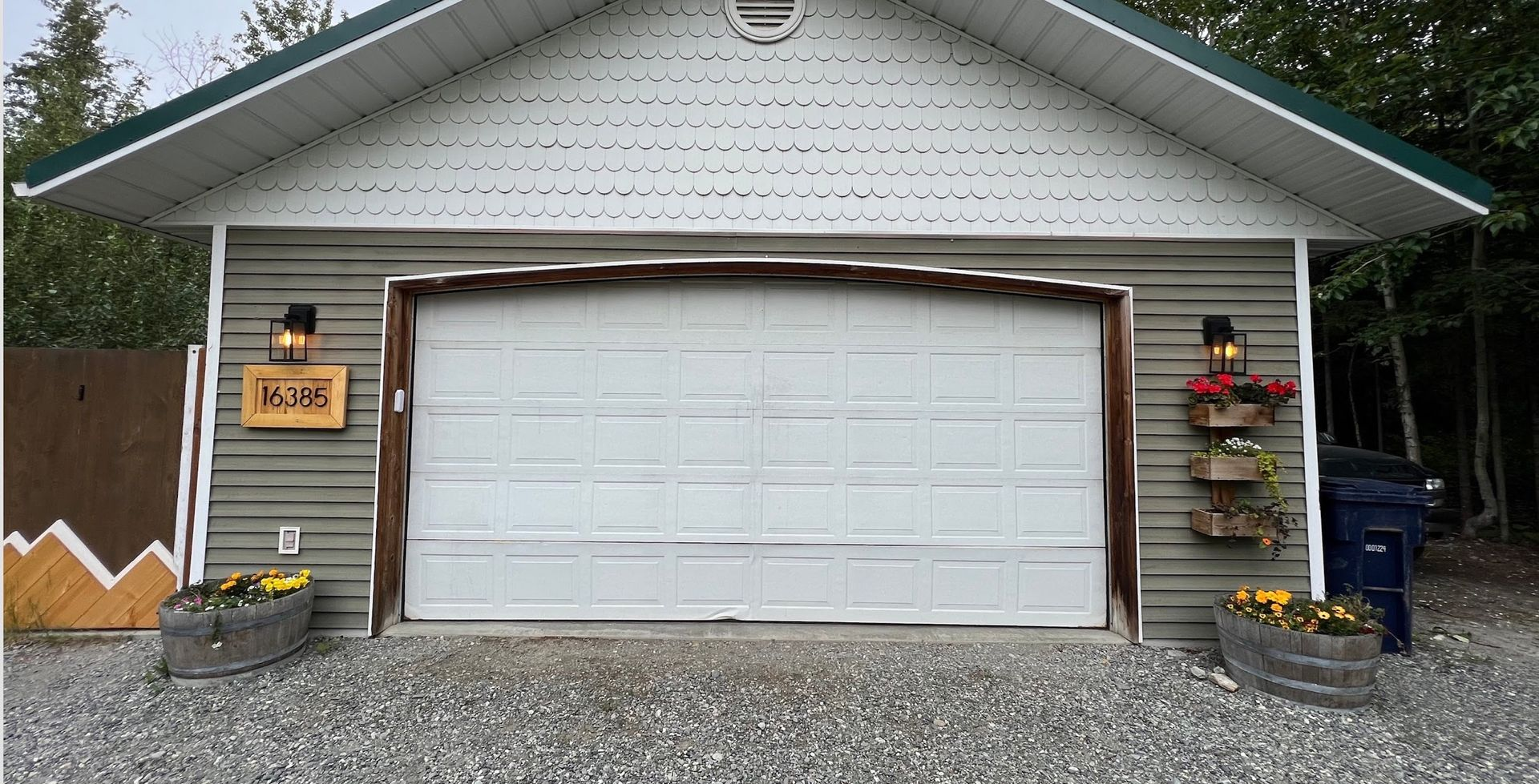 Garage with closed white door, green roof, and flower boxes.