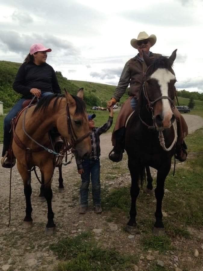 A Man and a Woman Are Riding Horses With a Child Standing Next to Them