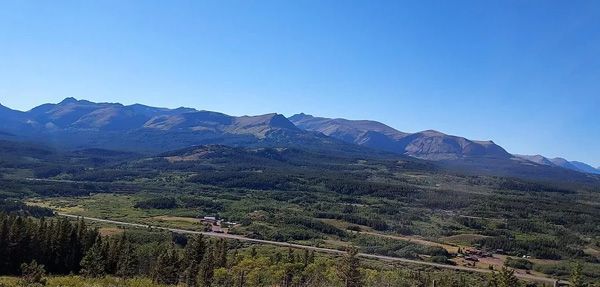 A View of a Mountain Range With Trees and a Road in the Foreground