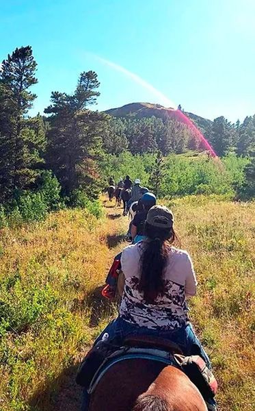 A Group of People Are Riding Horses Through a Grassy Field
