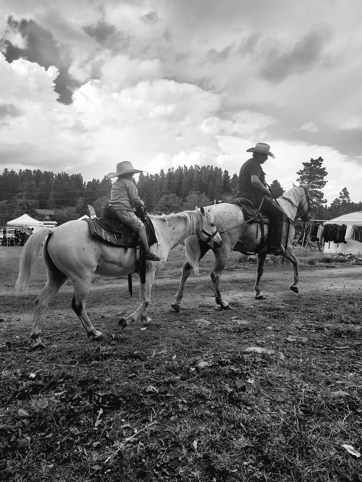 A Black and White Photo of Two People Riding Horses in a Field