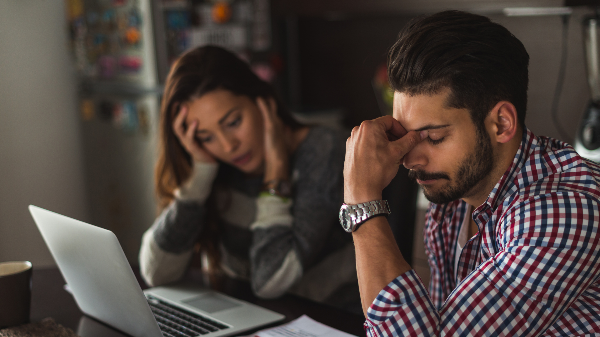 Couple looking stressed at laptop, likely working on finances.