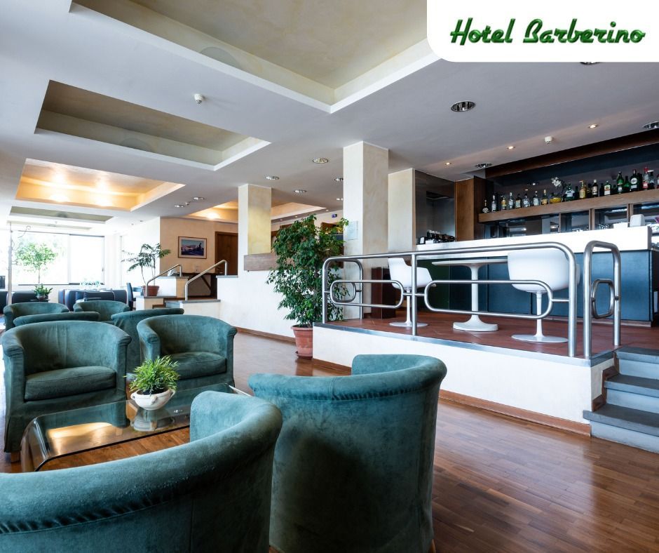 Una hall dell'hotel con sedie verdi e un bar