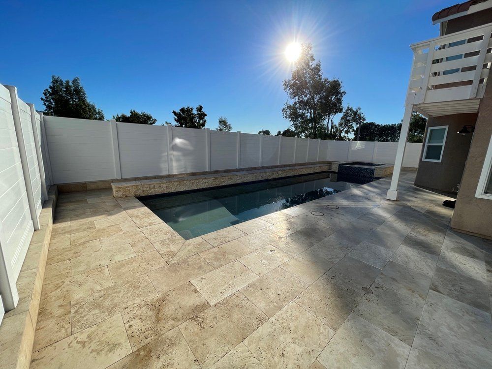 A large swimming pool is surrounded by a white fence.