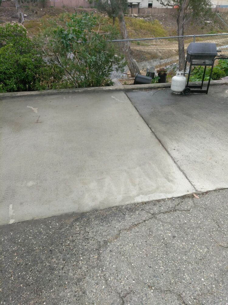 A concrete driveway with a grill and a propane tank on it.