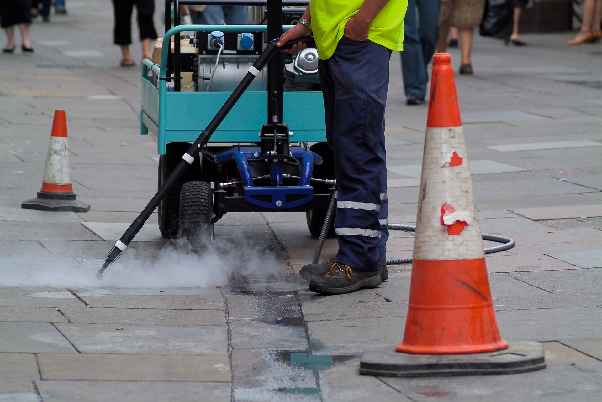 A man is cleaning the sidewalk with a machine