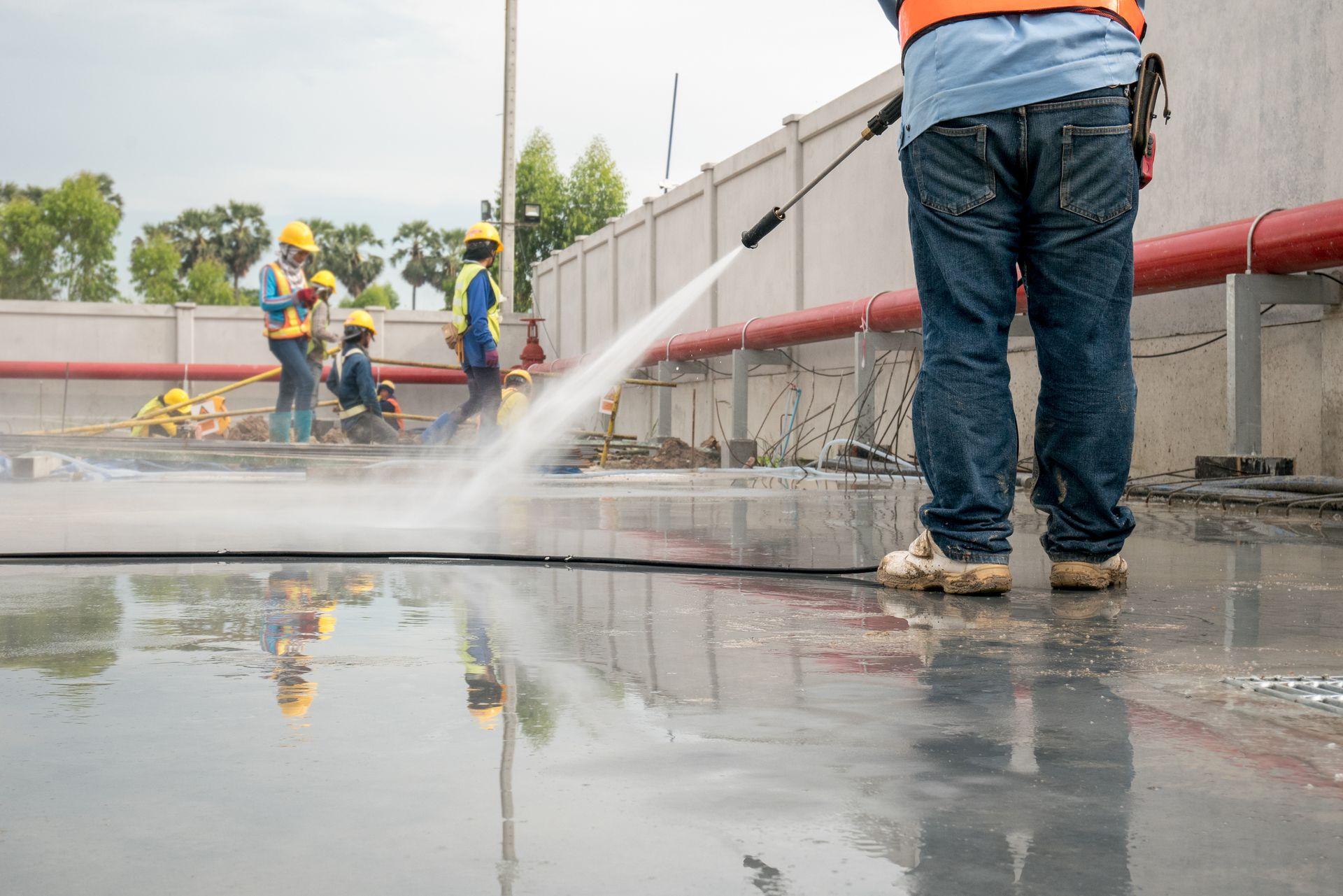 A man is using a high pressure washer to clean a concrete floor.