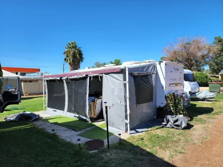 fully enclosed grey caravan annex with privacy screens attached to a white caravan