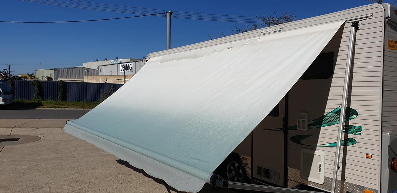 long, white caravan awning with a noticeable fading and discoloration to light green at the bottom edge