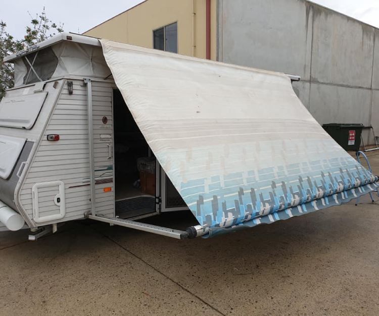 Grey pop-top caravan awning with a patterned blue and white awning fully extended for shade.