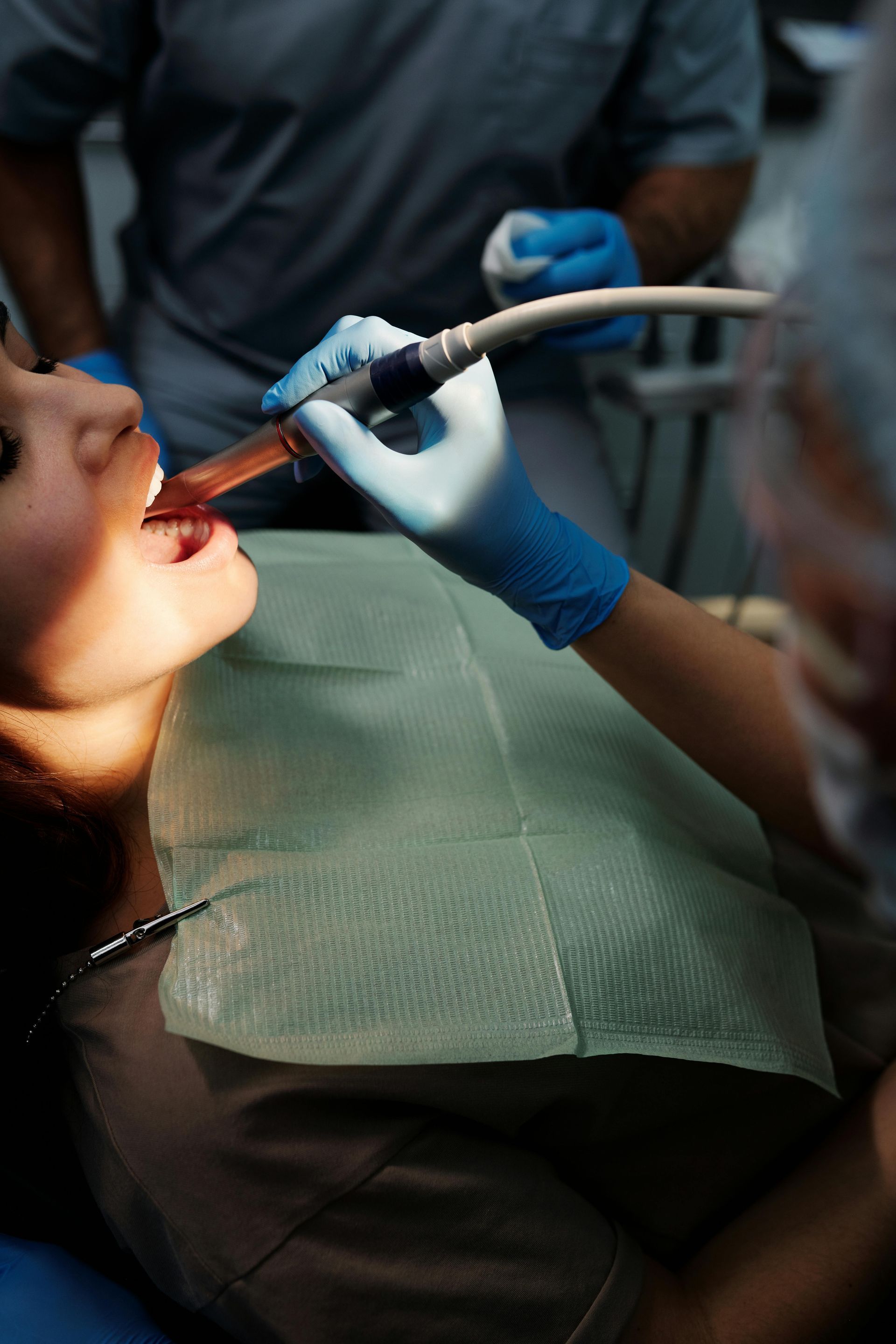 Dentist working on a patient's open mouth with dental tools in a clinic setting.