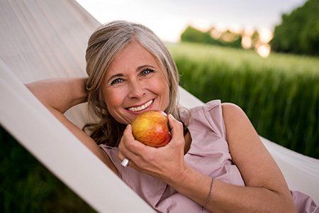 older woman eating an apple | restorative dentistry | Dentist Near Me Wellington