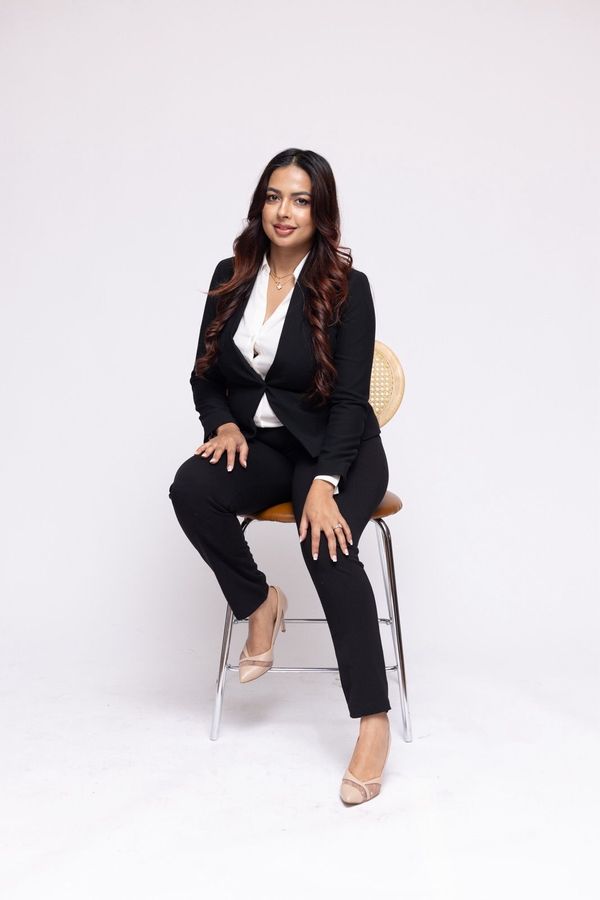 A woman in a suit is sitting on a chair.