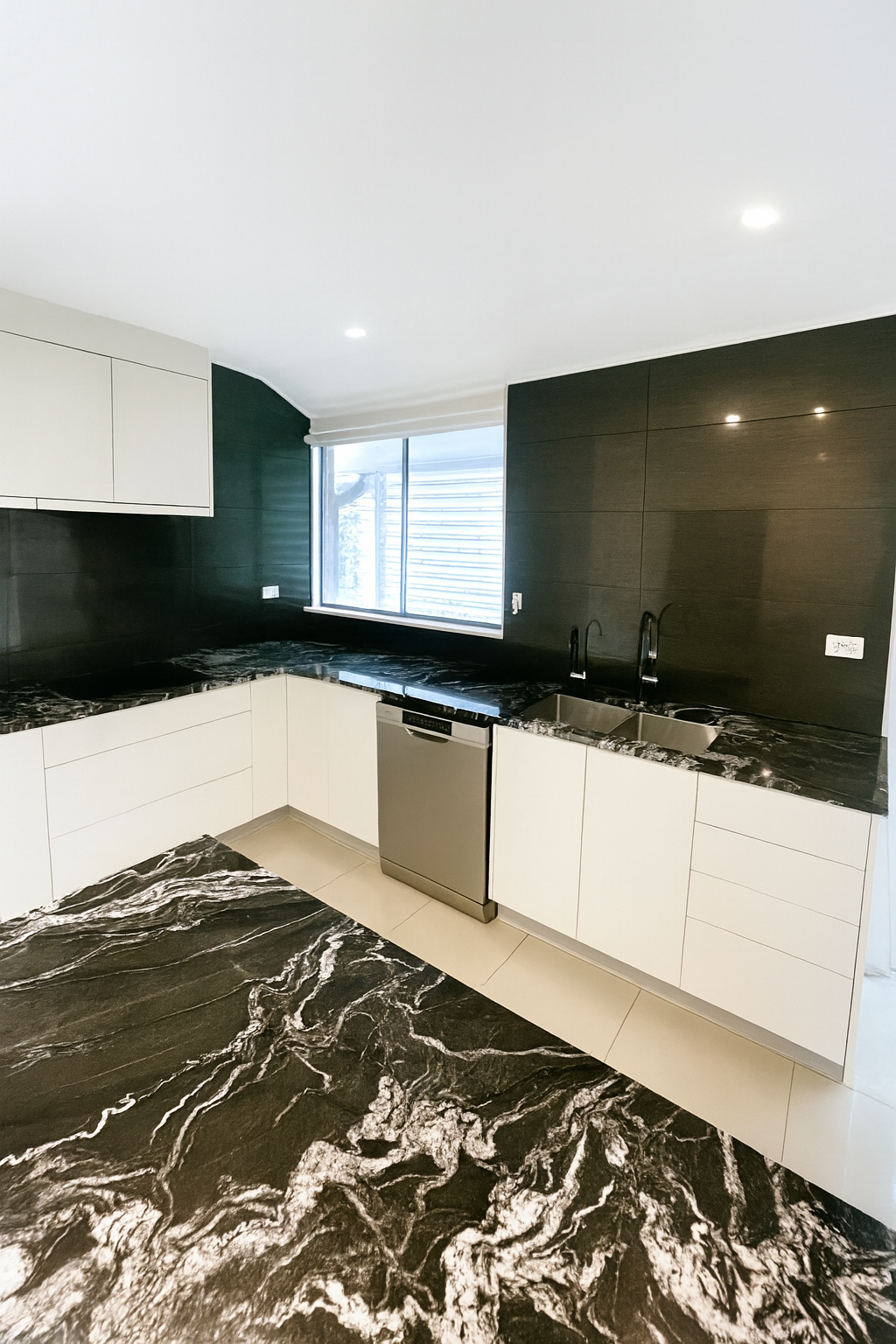 Modern kitchen with white cabinets, black countertops, and a black and white patterned floor.
