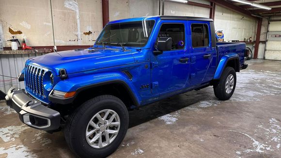 Blue Jeep Gladiator pickup in an indoor garage, angled front view
