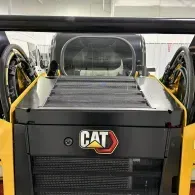 Yellow CAT construction machine in a factory, viewed from the front with open side panels.