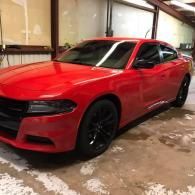 Red sports coupe parked indoors on a wet concrete floor, with black wheels.