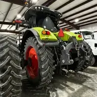 Rear view of a lime-green tractor with red wheels inside a large barn or shed