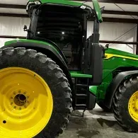 Green and yellow John Deere tractor in a barn, side view