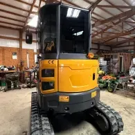 Yellow and black mini excavator inside a workshop with tracked wheels
