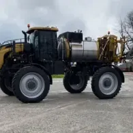 Large black agricultural sprayer truck with silver tank parked on a snowy road