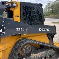 Yellow and black John Deere 325G compact track loader with muddy tracks outdoors