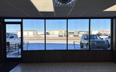 Empty storefront interior with large windows overlooking a snowy parking lot and parked trucks.