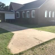 Suburban brick house with a concrete driveway and front lawn in bright sunlight