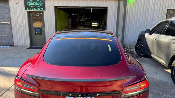 Red sports car parked outside a garage with a white car beside it