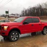 Red pickup truck parked on a wet lot on an overcast day.
