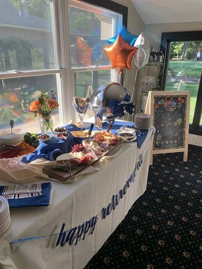 A buffet table with balloons and a banner that says `` happy retirement ''.