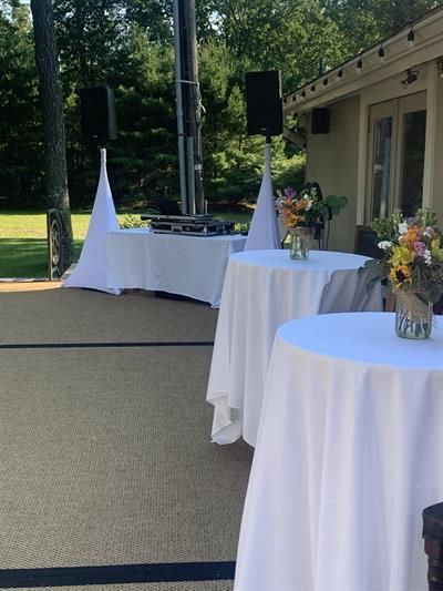 Tables with white covers and vases of flowers on them