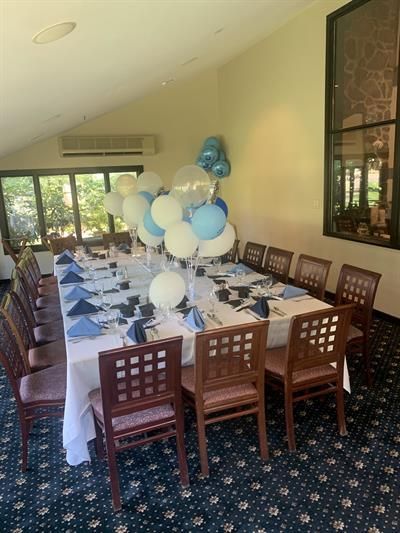 A long table with balloons on top of it in a room.