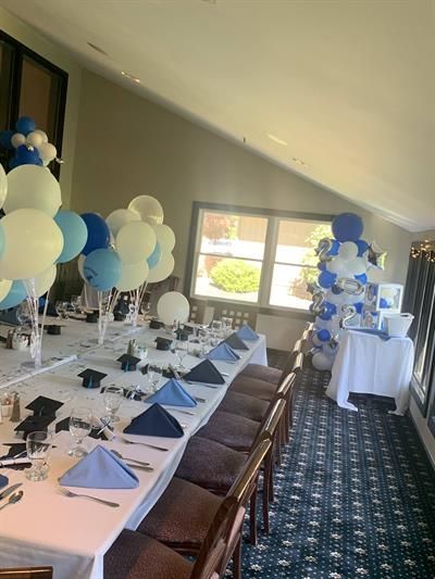 A long table with balloons on it is sitting in a room.