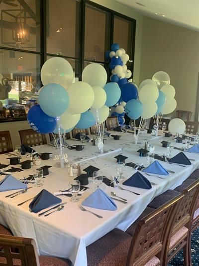 A long table with blue and white balloons on it