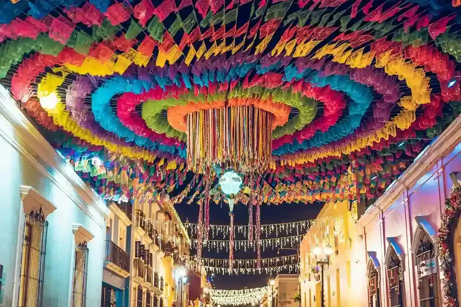 Por la noche, coloridas guirnaldas de papel picado cuelgan en círculos concéntricos sobre una estrecha calle mexicana.