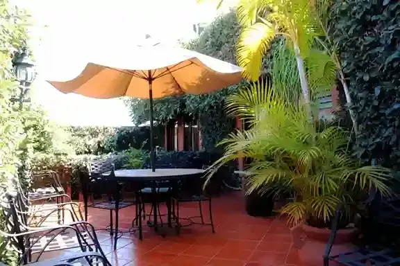Un patio con una mesa redonda y una sombrilla color canela.
