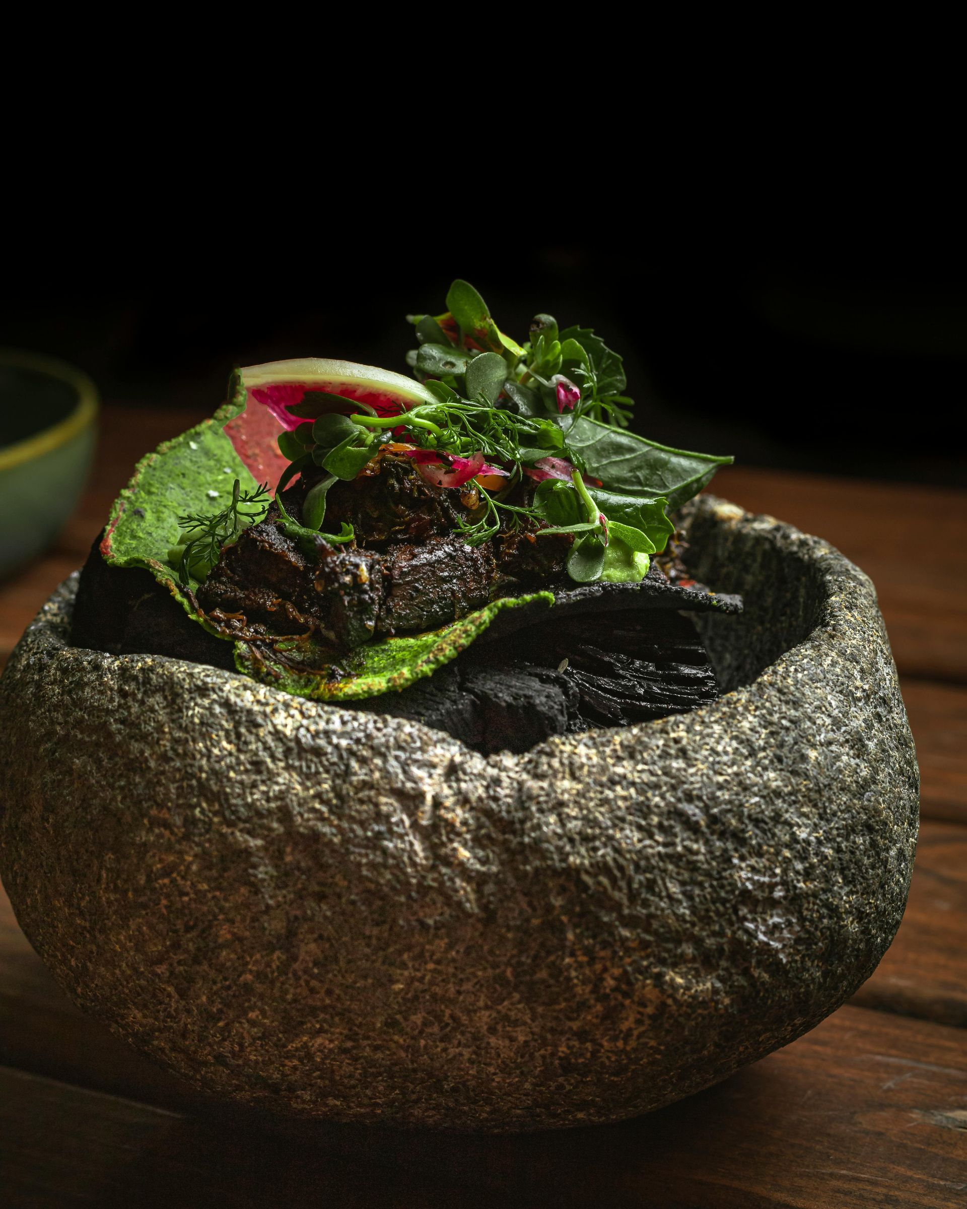 Trolebuses coloridos estacionados en un terreno pavimentado, bajo un cielo brillante con árboles verdes en el fondo.
