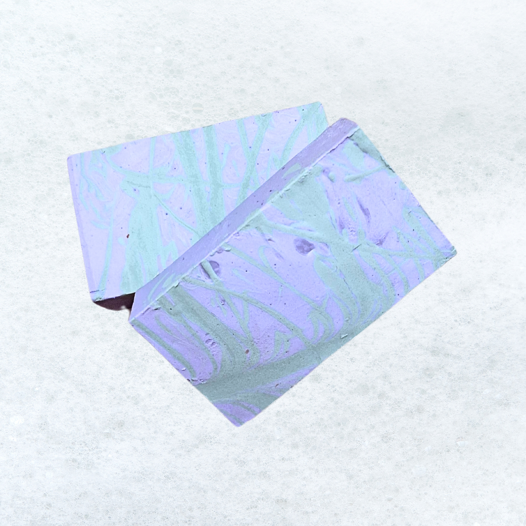 Two pieces of soap are stacked on top of each other on a wooden table.