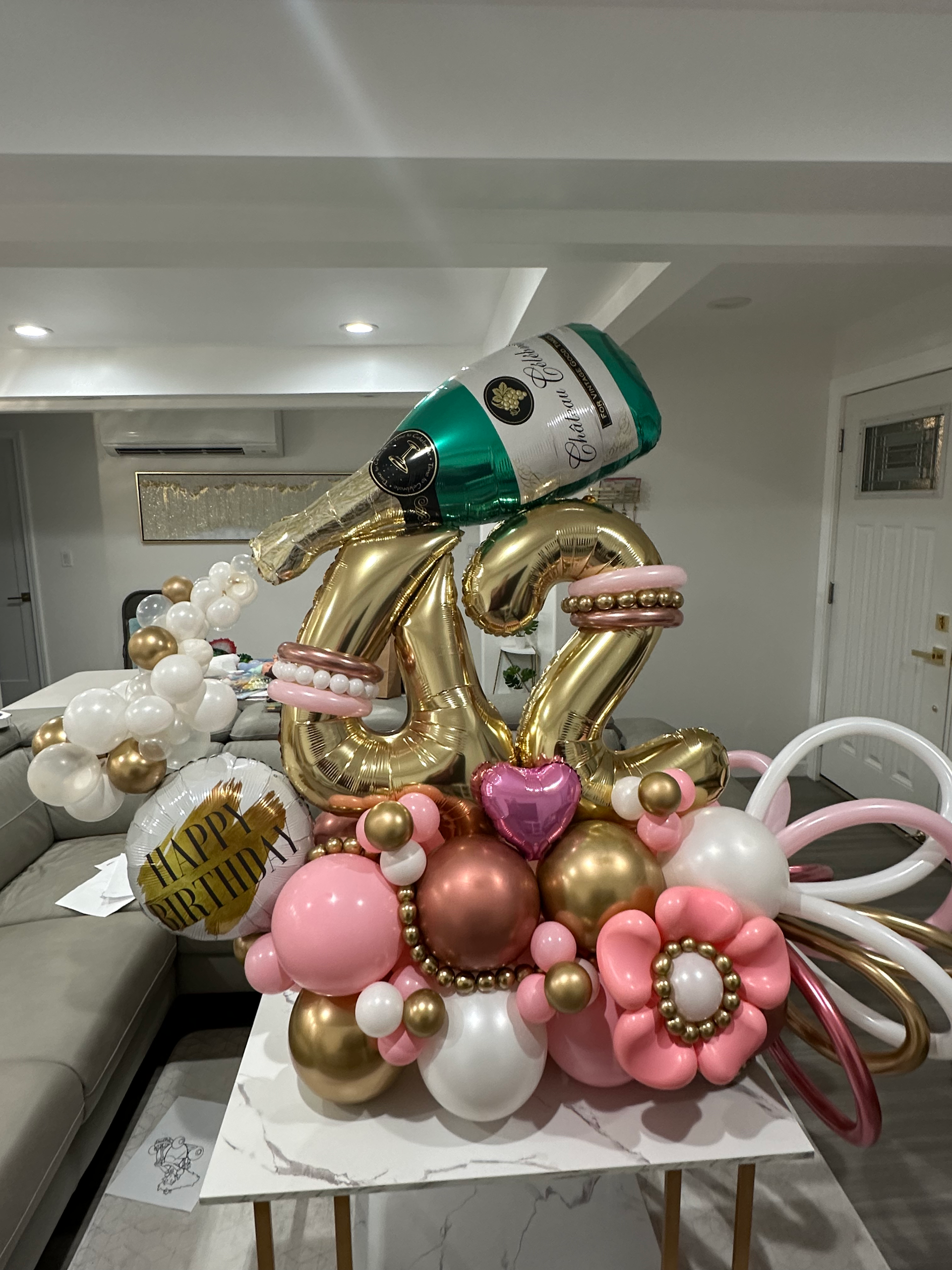 A table topped with balloons and a bottle of champagne.