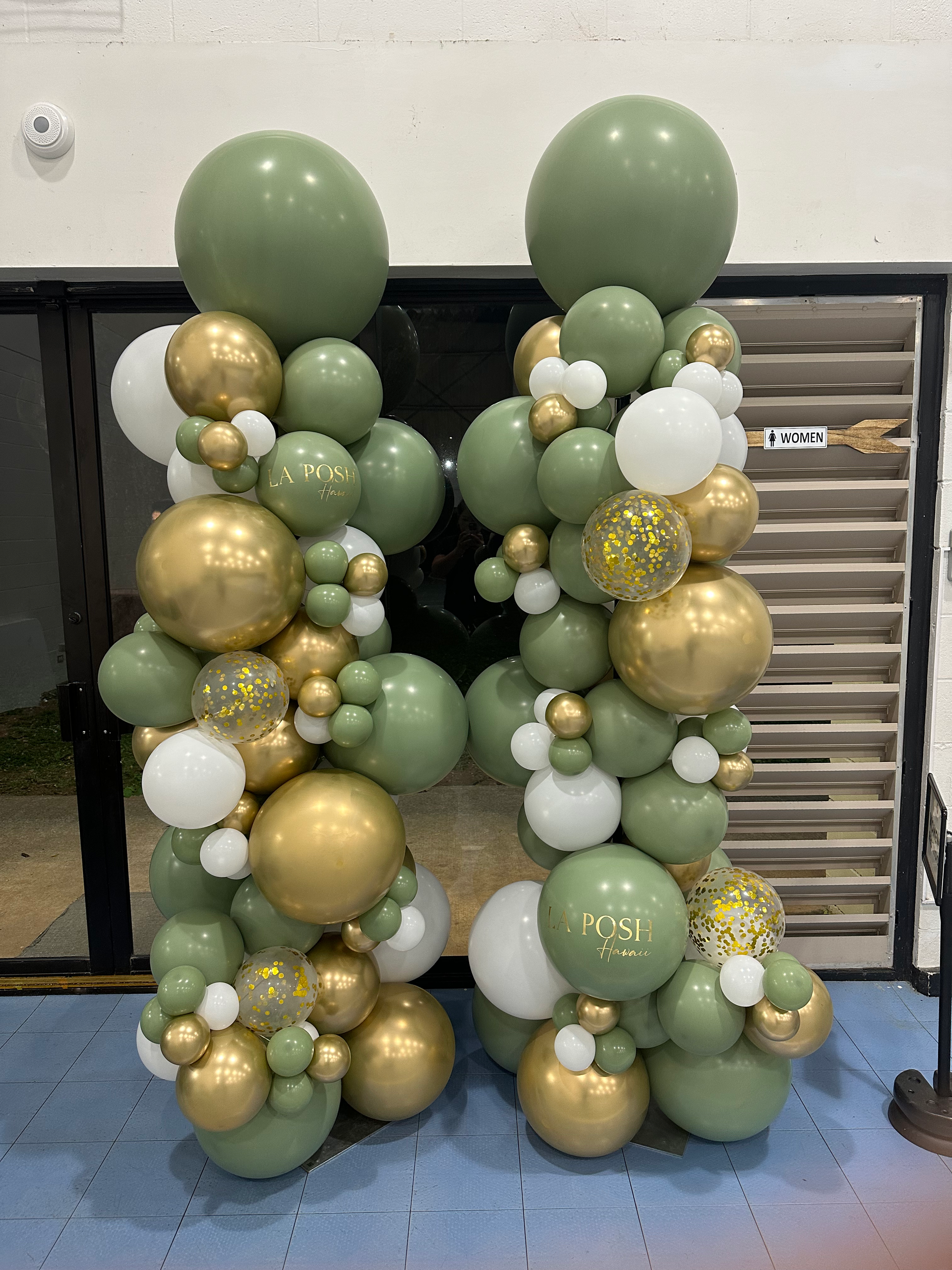 A bunch of green and gold balloons are stacked on top of each other.