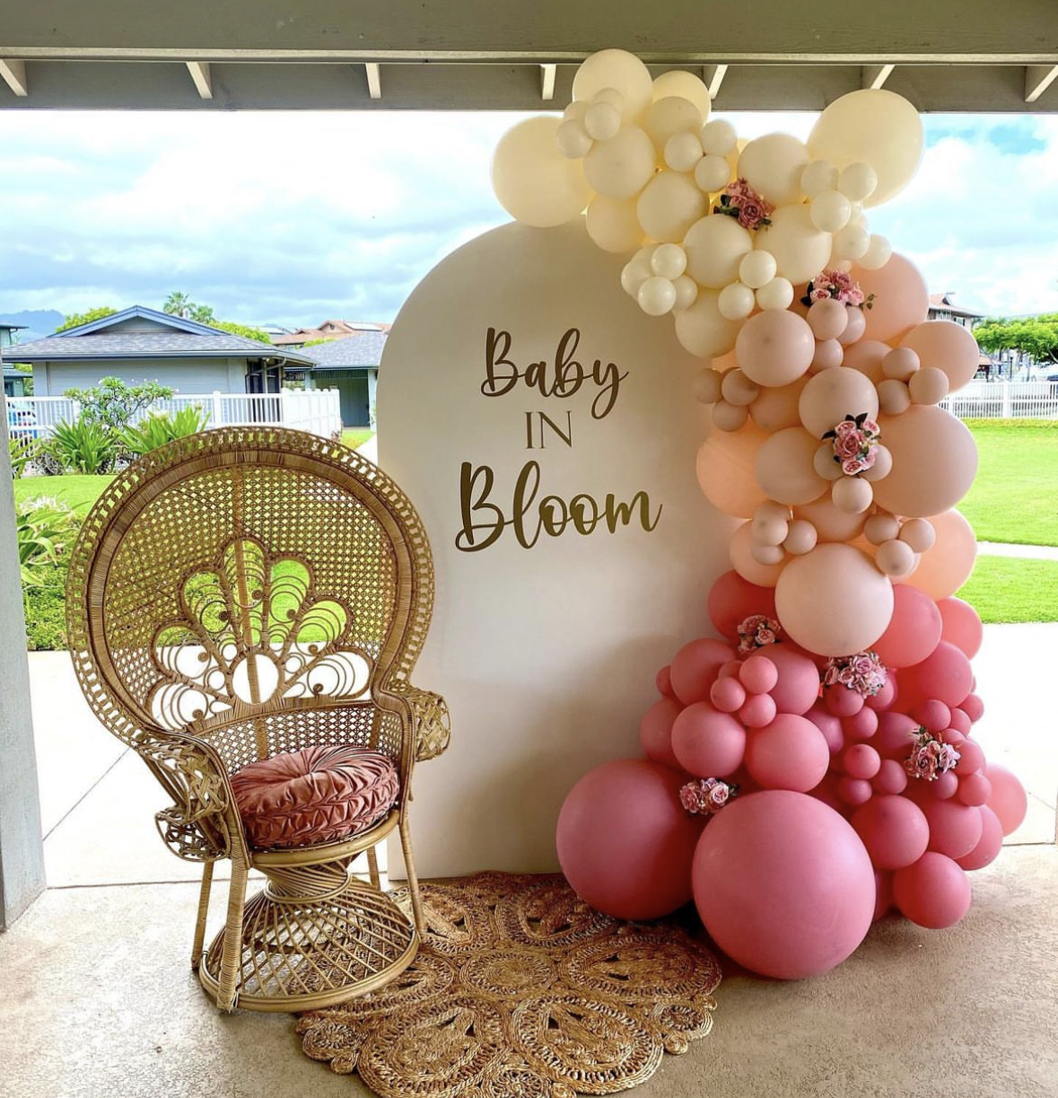 A wicker chair is sitting in front of a wall decorated with pink balloons.