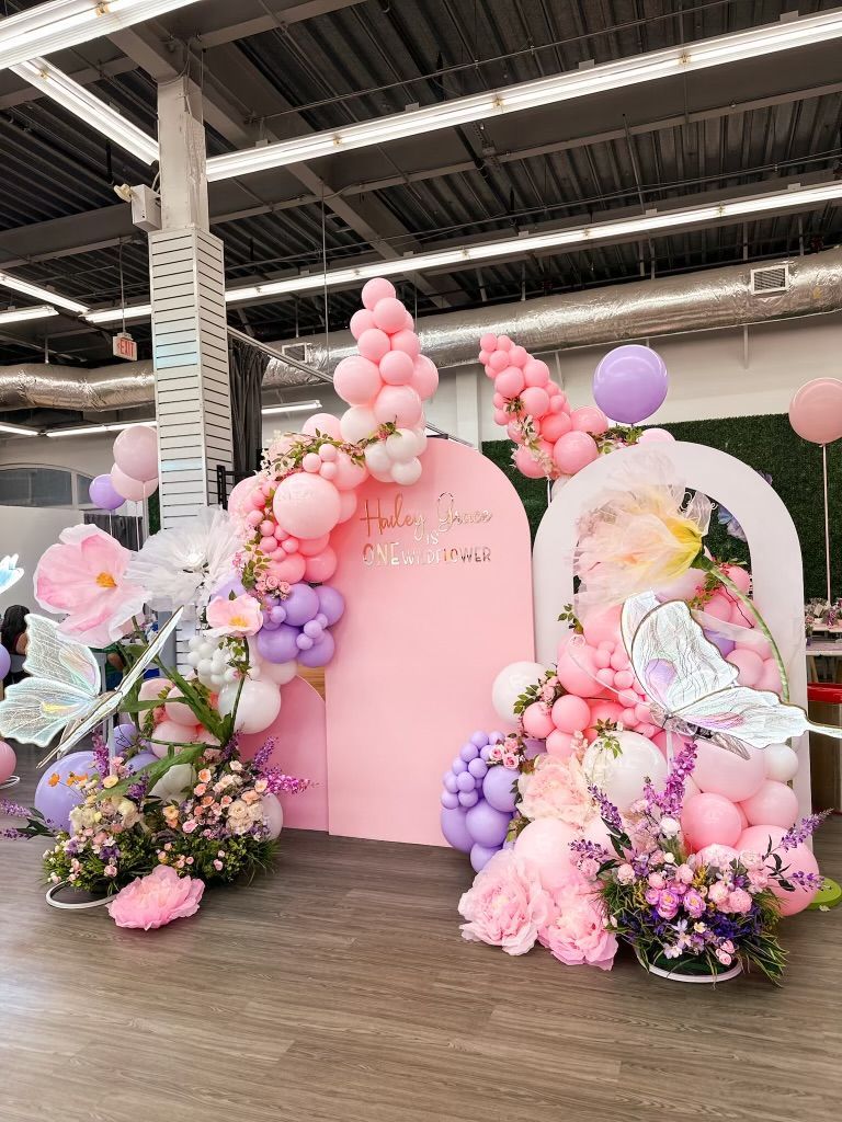 A room filled with pink and purple balloons and flowers.