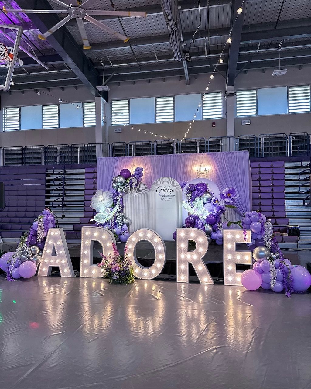 The word adore is surrounded by purple balloons and lights.