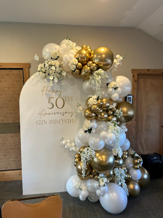 A wall decorated with balloons and flowers for a 50th anniversary.