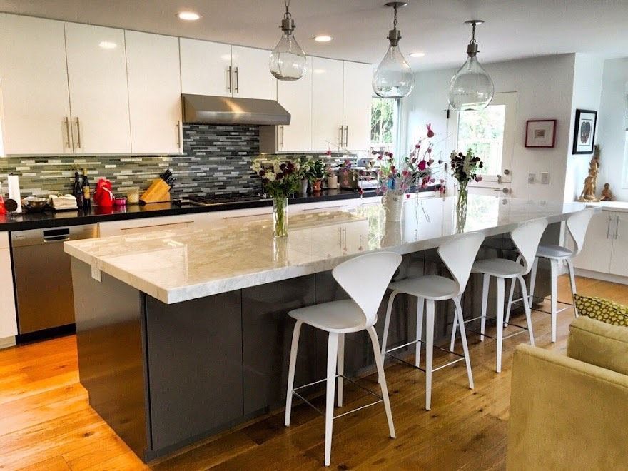 Modern kitchen with white and gray cabinets, island with stools, and pendant lights.