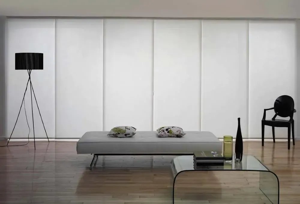 Two vases with dried flowers are sitting on a window sill in front of a window with blinds.