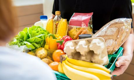 A person is holding a basket of fruits and vegetables.